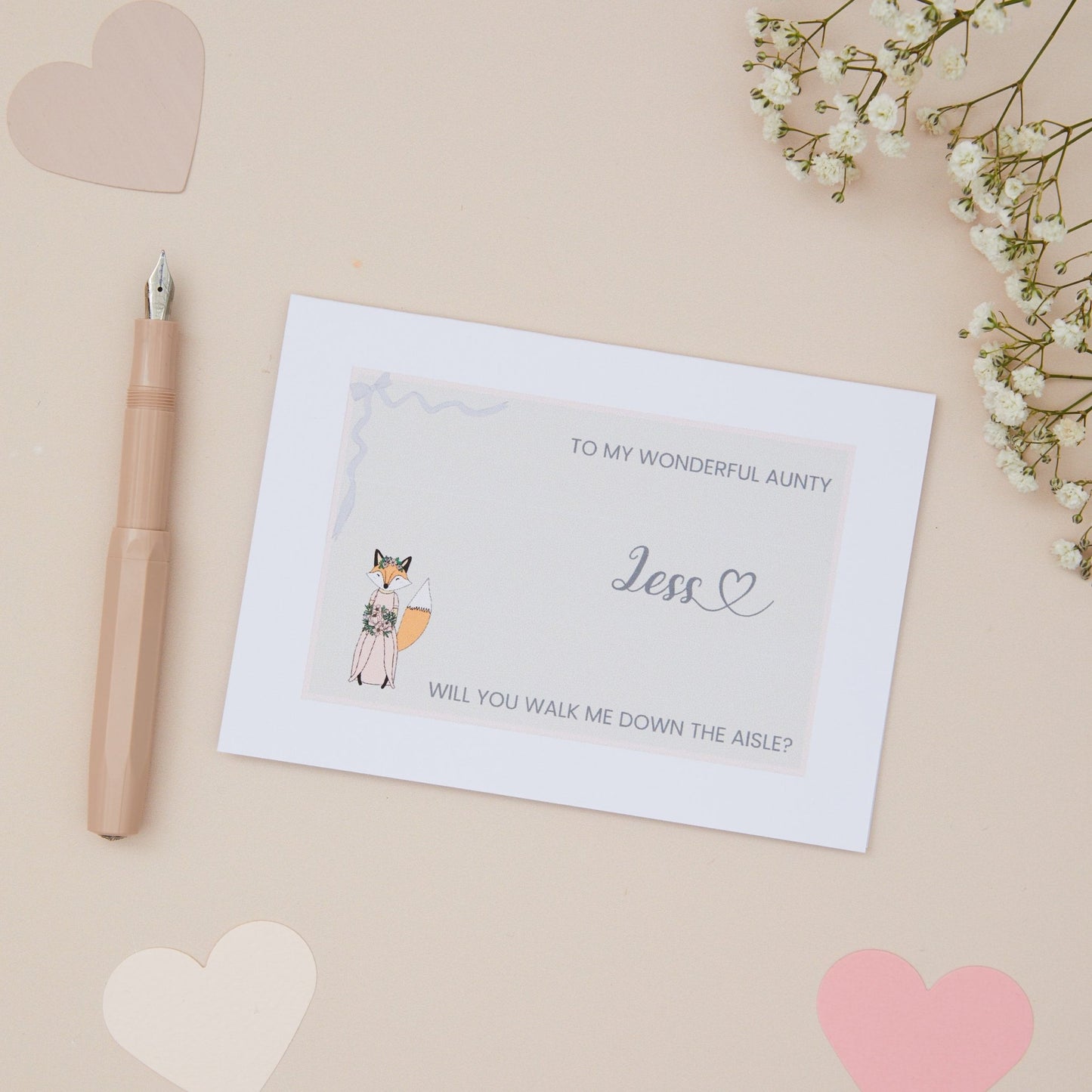 Aunty will you walk me down the Aisle proposal Card. A Girl Fox her bridal attire with the label 'To my wonderful Aunty, will you walk me down the aisle. The Card is set against a pale beige background with stationery items.