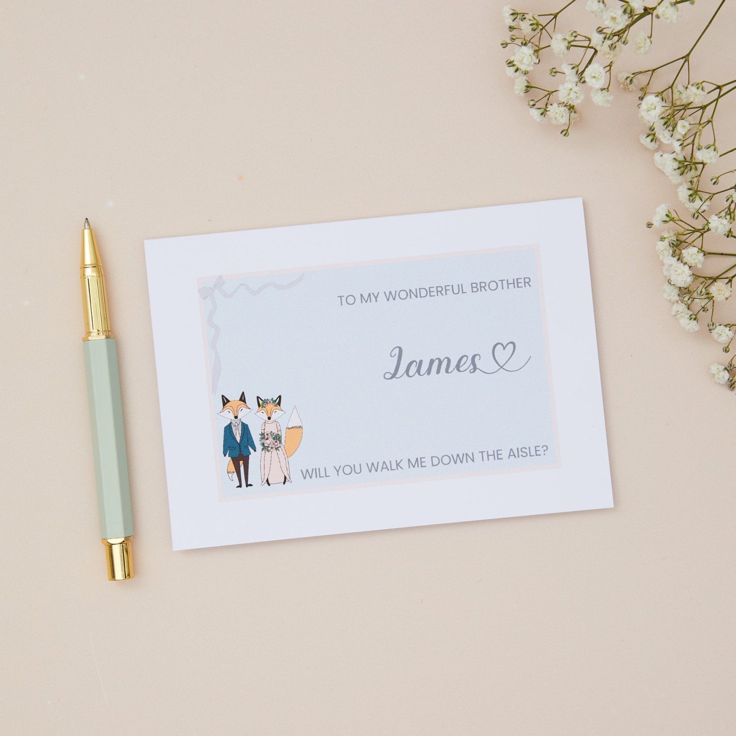 Brother will you walk me down the Aisle proposal Card. A Fox couple with bridal attire with the label 'To my wonderful Brother, will you walk me down the aisle. The Card is set against a pale beige background with stationery items.