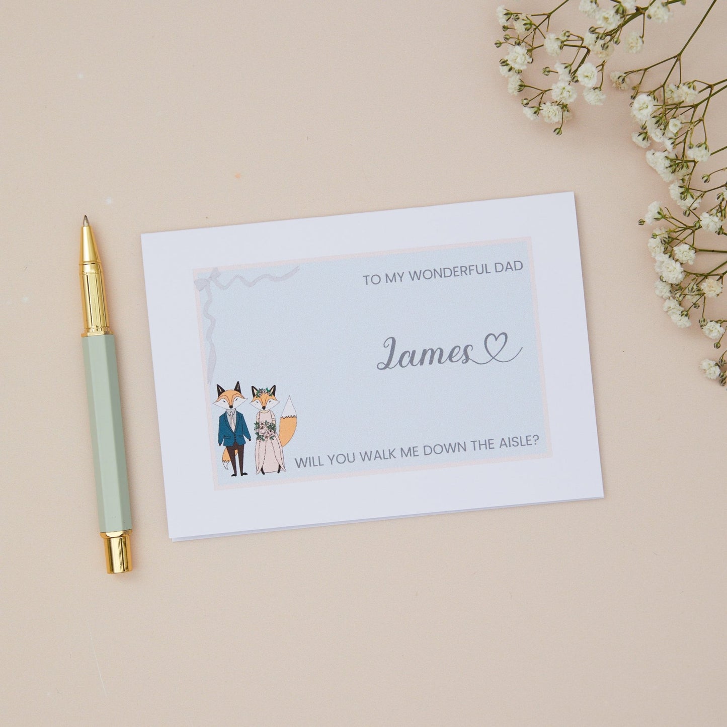 Dad will you walk me down the Aisle proposal Card. A Girl couple in wedding bridal attire with the label 'To my wonderful Dad, will you walk me down the aisle. The Card is set against a pale beige background with stationery items.