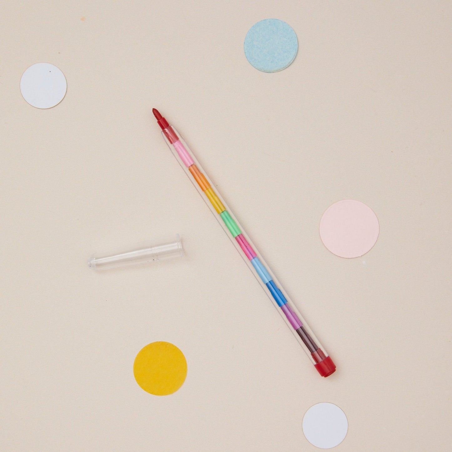 Multicolored pen on a beige background with colourful dots