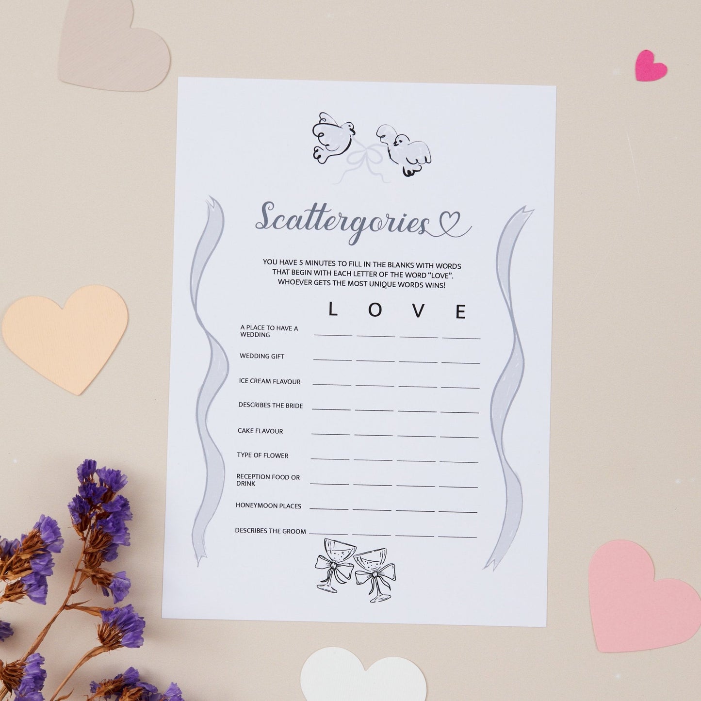A5 sized wedding reception game card titled 'Scattergories' with spaces for writing the words that have been mixed up but all relate to the word love. Decorated with a heart and ribbon design, displayed on a neutral background with some decorative hearts and flowers.