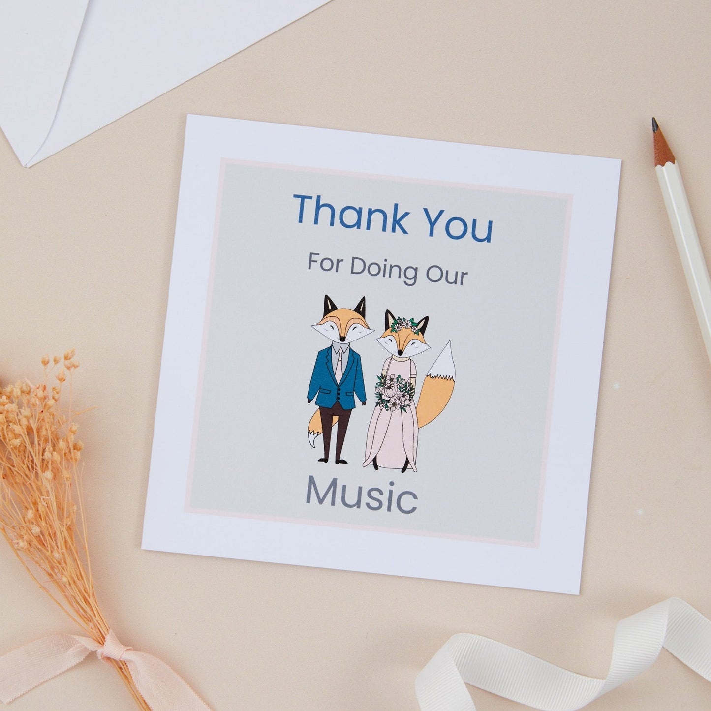 A square greeting card with a 'Thank You For Doing Our Music' message, featuring illustrations of a fox couple placed on a neutral background with a pen, ribbon, and envelope.