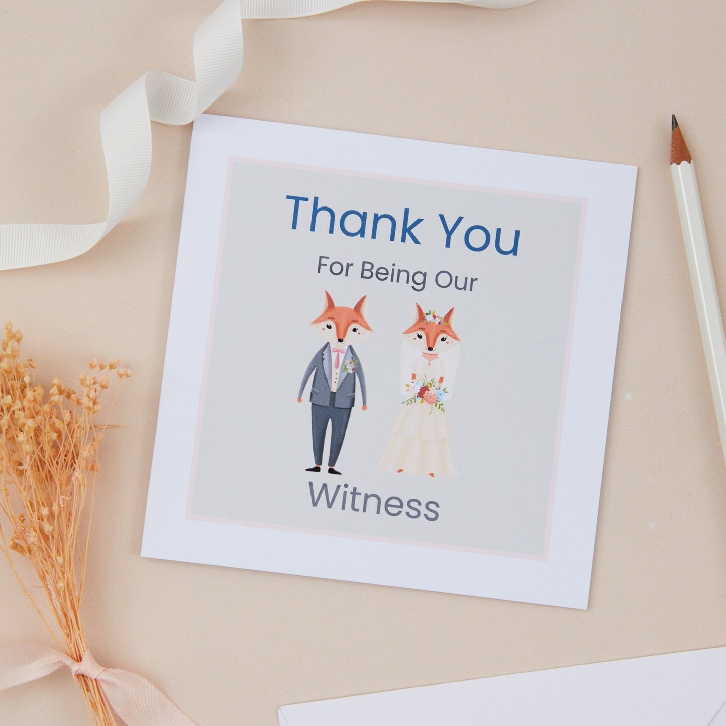 A 'Thank You for Being Our Witness' wedding thank you card featuring an illustration of a fox couple in formal attire. The card is placed on a neutral background with a ribbon and a pencil for scale.