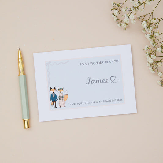 Uncle Thanks for walking me down the Aisle Card. A Fox Couple in their bridal attire with the label 'To my wonderful uncle thank you for walking me down the aisle. The Card is set against a pale beige background with stationery items.