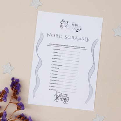 A5-sized 'Wedding Scrabble' game card with a list of words to create a scramble, printed on high-quality 250gsm cardstock, displayed on a table with purple flowers and star decorations in the background.