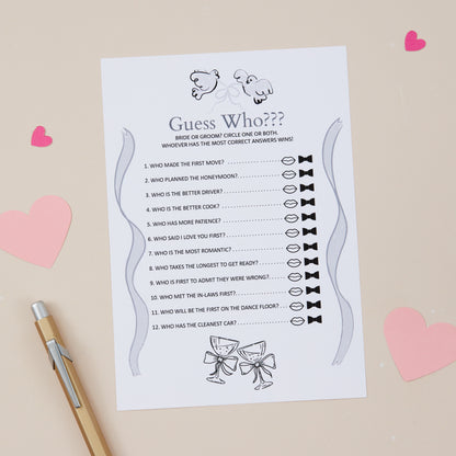 A printed 'Guess Who?' wedding game card where guests have to guess whether the statements listed are more likely to relate to the bride or the groom. The Card is on a beige background with pencil and heart-shaped decorations on the table.